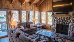 A cozy wooden interior with a fireplace, large windows, and a comfortable seating area. - Lake Views! Perfect Mountain Summer Get-a-way No traffic, 8,000 ft. elevation (Stateline)
