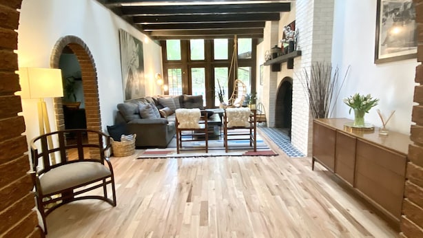 A spacious living room with a wooden floor, a fireplace, and a large window.