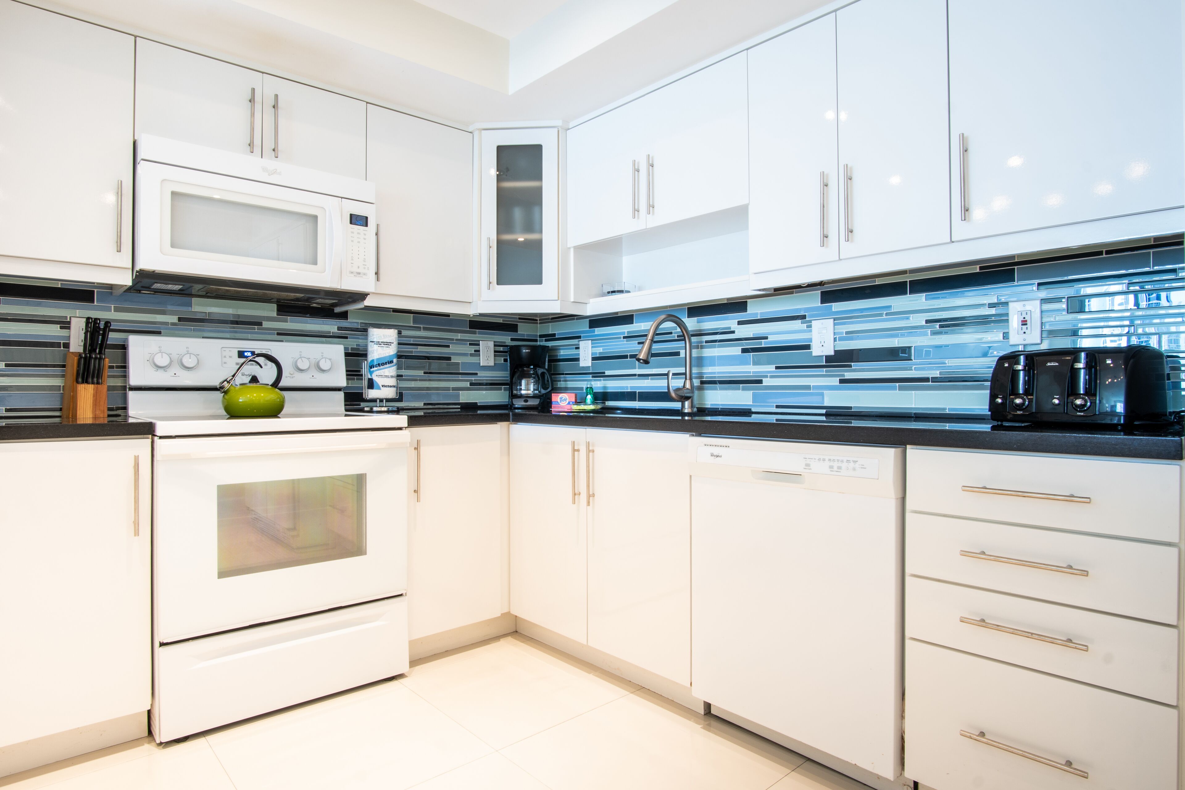 A modern kitchen with white cabinetry, a microwave, a stove, and a dishwasher.