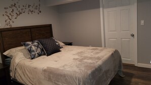 Un dormitori amb llit, una tauleta de nit, una decoració penjada a la paret i una porta.