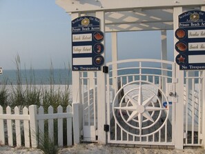 A gated beach entrance with signs indicating private beach access and no trespassing.