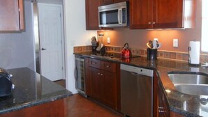 A kitchen with wooden cabinets, a microwave, a dishwasher, and a granite countertop. - Model 3 Bedrm with office/den  second floor with stunning mountain views (Tucson)