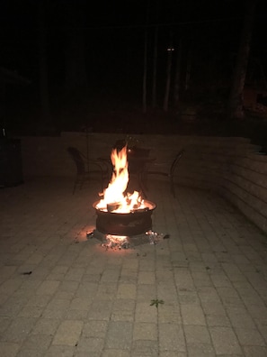 Bålsted med flammer i et belagt udendørs område.