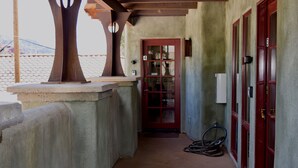 A narrow corridor with a red door, a white electrical box, and a bicycle leaning against the wall. - Walk a Block to Uptown, to the main shops, tours, restaurants. (Sedona)