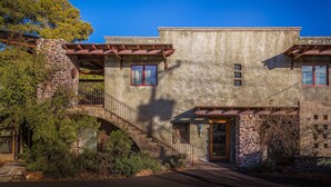 A two-story stone building with a stone staircase, a balcony, and a wooden door. - Walk a Block to Uptown, to the main shops, tours, restaurants. (Sedona)