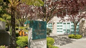 Ein Schild für Lombard Plaza mit einem modernen Gebäude im Hintergrund.