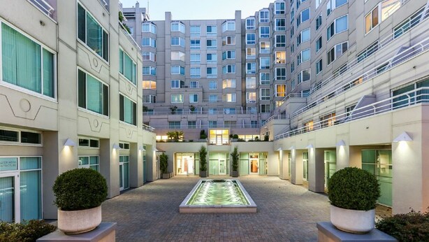Ein moderner Hotelinnenhof mit einem zentralen Pool, mehreren Balkonen und gut beleuchteten Wegen.