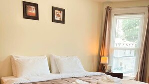 A neatly made bed with a brown quilt, white pillows, and folded towels on a wooden floor. - After the Game Apt 1 - All Star Baseball Rentals (Oneonta)