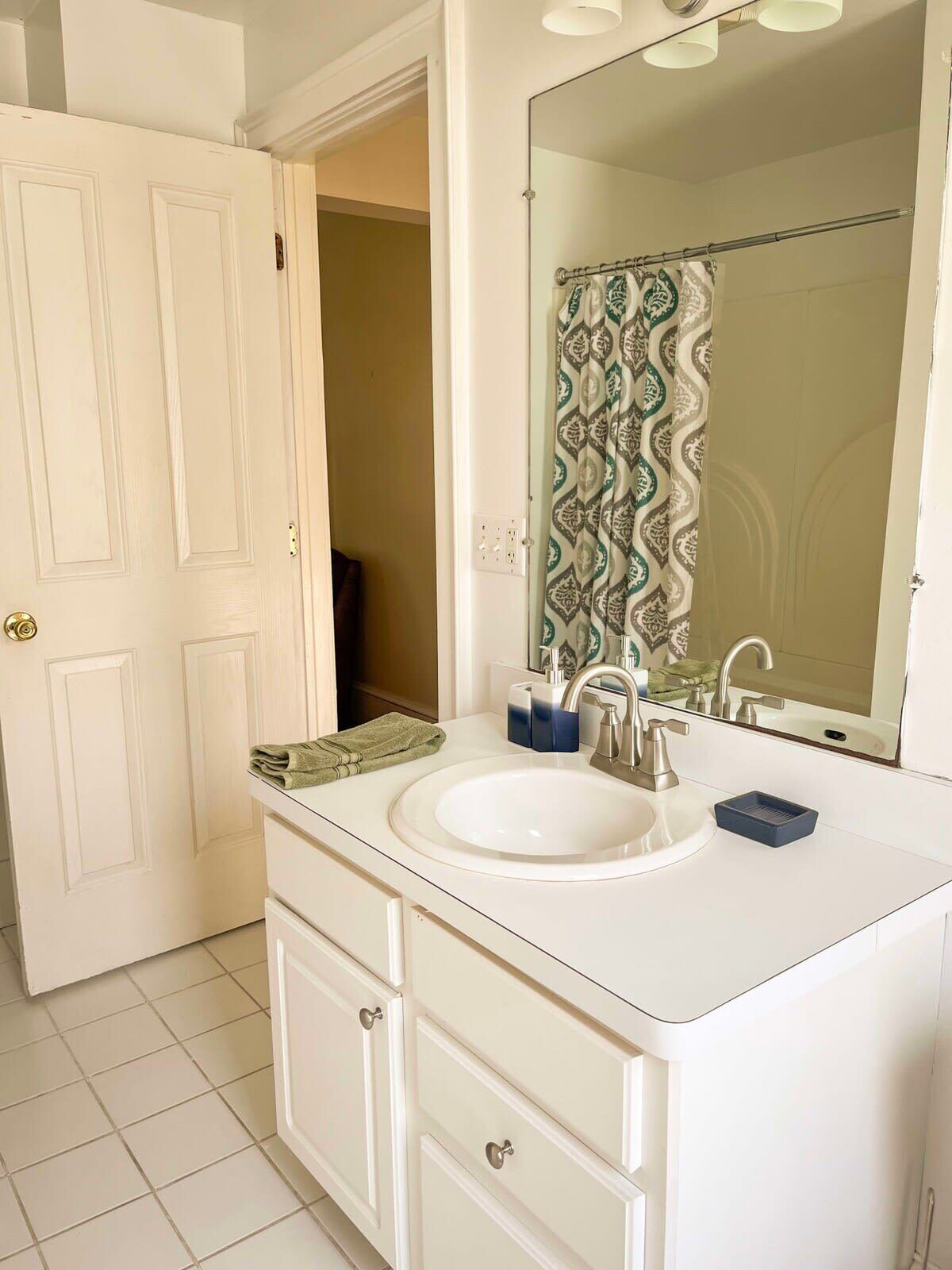 A bathroom with a white sink, a mirror, and a shower curtain.