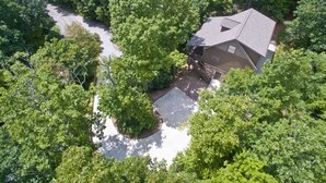 Una vista aerea di una casa circondata da alberi fitti, con un vialetto che conduce all'ingresso.