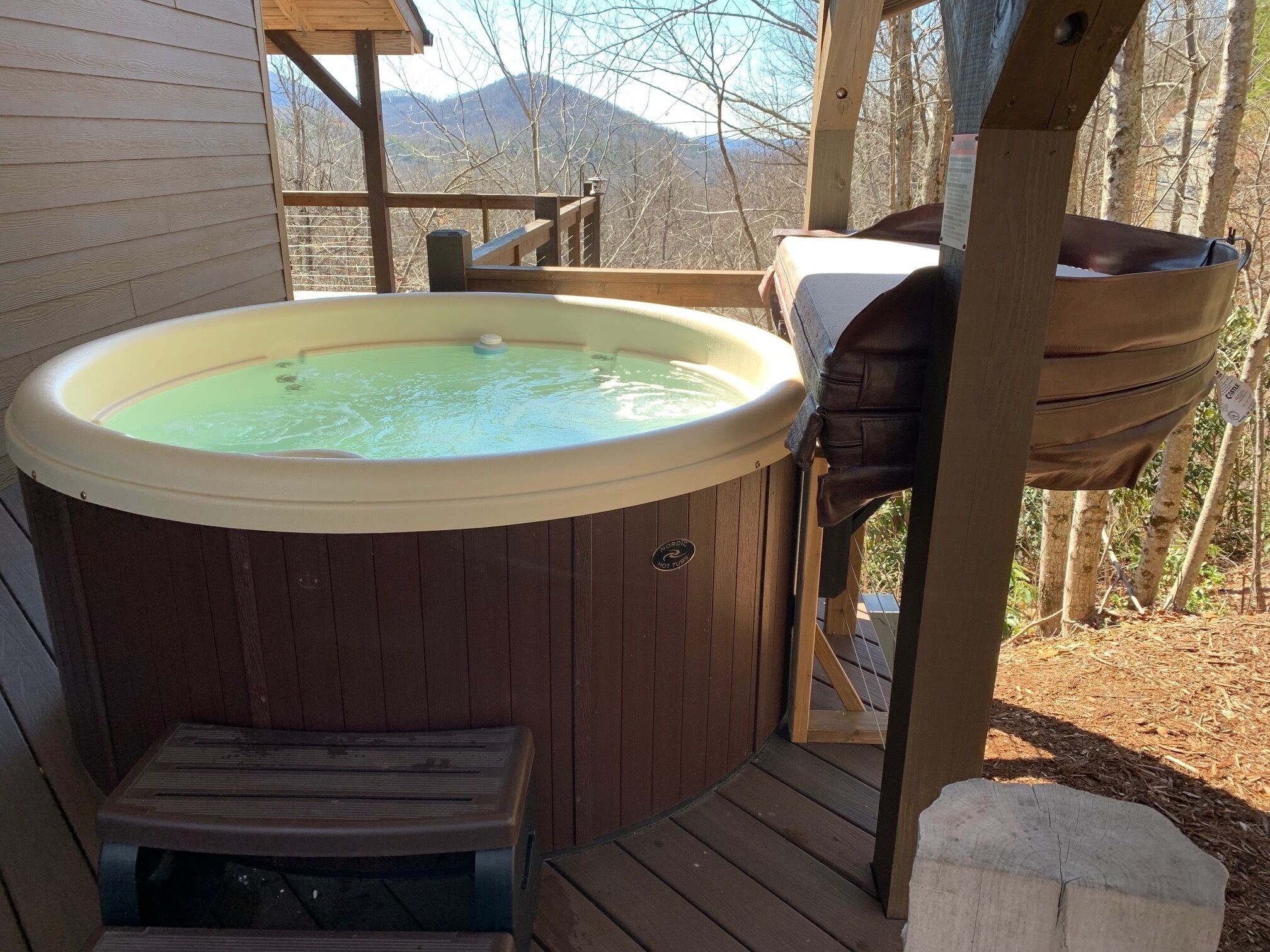 Un bain à remous sur une terrasse en bois, avec vue sur les montagnes.