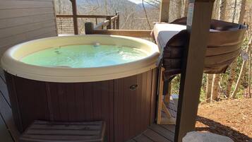 Un bain à remous sur une terrasse en bois, avec vue sur les montagnes.