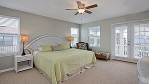 Quarto com cama, mesas de cabeceira, uma cadeira e ventilador de teto.