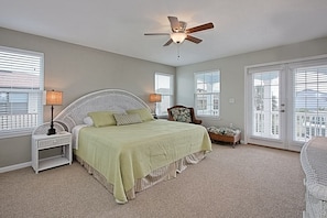 A bedroom with a bed, nightstands, a chair, and a ceiling fan.