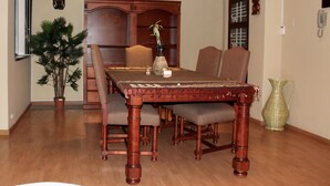 A dining area with a wooden table, chairs, a vase with a plant, and decorative items on the wall.