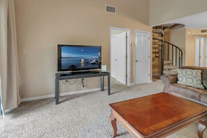 Relax in this stylish living room with a flat-screen TV, comfortable sofa, and spiral staircase.