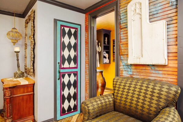 A room with a checkered sofa, a decorative lamp, and a door with a colorful diamond pattern.