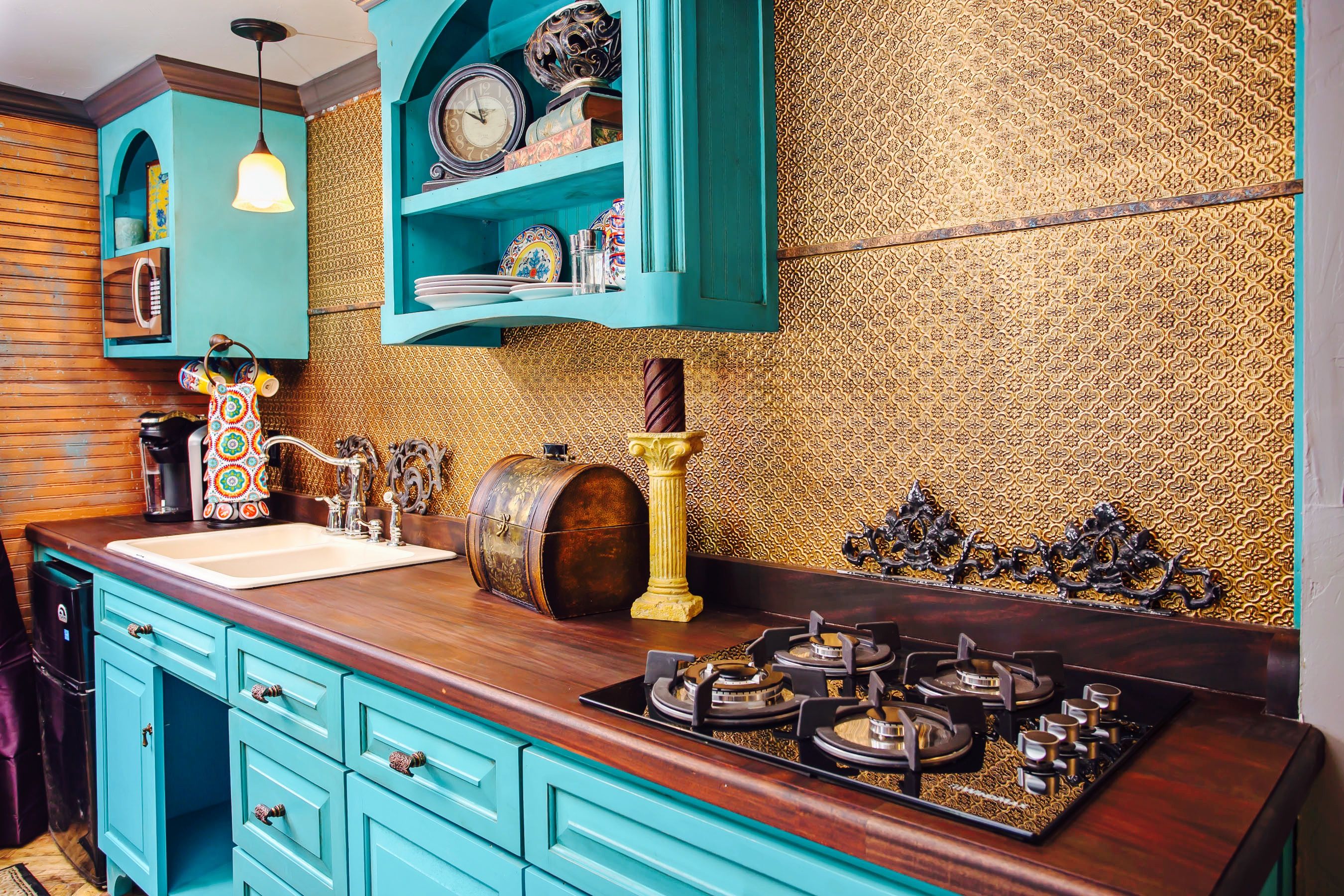 A kitchen with teal cabinets, a wooden countertop, a gas stove, and decorative items.