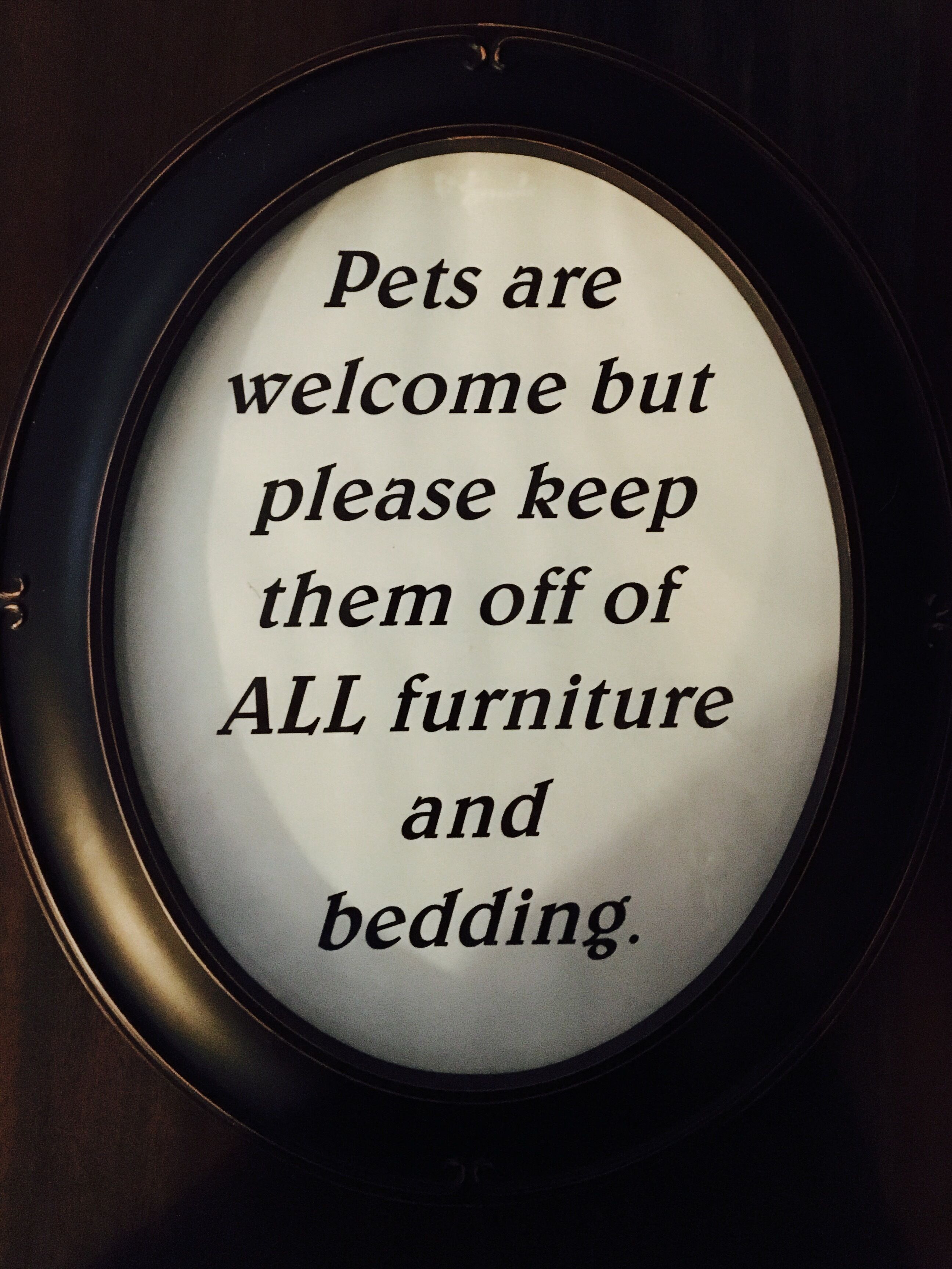 A framed sign with a message about pet policy.