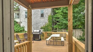 A wooden deck with a grill, chairs, and a picnic table.