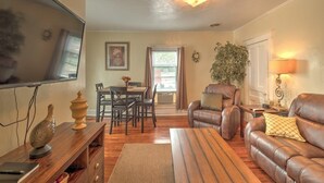 A living room with a television, a dining table, chairs, a sofa, and a fireplace.