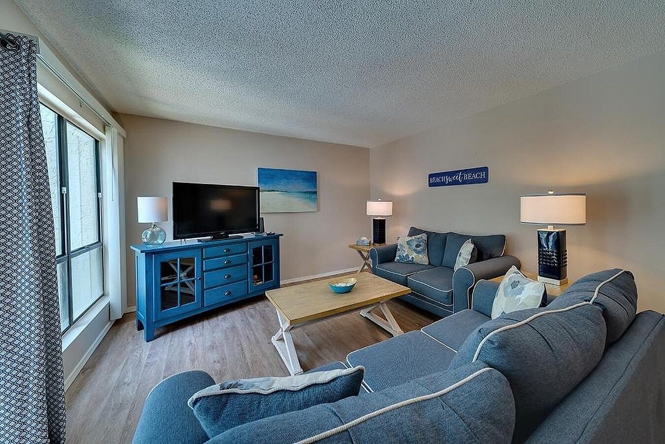 A living room with a TV, sofa, coffee table, and lamps.