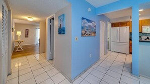 A hallway with a blue wall, a white refrigerator, and a dining area with wooden cabinets. - 2 bedroom, 3 beds, 2 1/2 bath Duplex on Siesta Key • Heated Pool & Fishing Dock (Siesta Key)