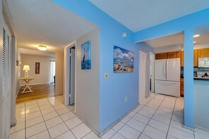 A hallway with a blue wall, a white refrigerator, and a dining area with wooden cabinets. - 2 bedroom, 3 beds, 2 1/2 bath Duplex on Siesta Key • Heated Pool & Fishing Dock (Siesta Key)