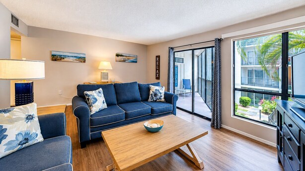 A modern living room with a sofa, coffee table, and a view of the outside. - 2 bedroom, 3 beds, 2 1/2 bath Duplex on Siesta Key • Heated Pool & Fishing Dock (Siesta Key)