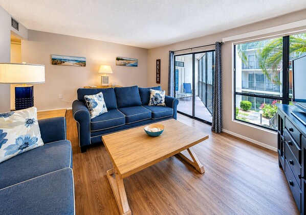 A modern living room with a sofa, coffee table, and a view of the outside.