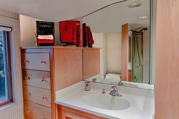 A bathroom with a wooden vanity, a large mirror, a white sink, and a glass shower enclosure. - Antique charm, modern amenities, lake and mountain views (Gilford)