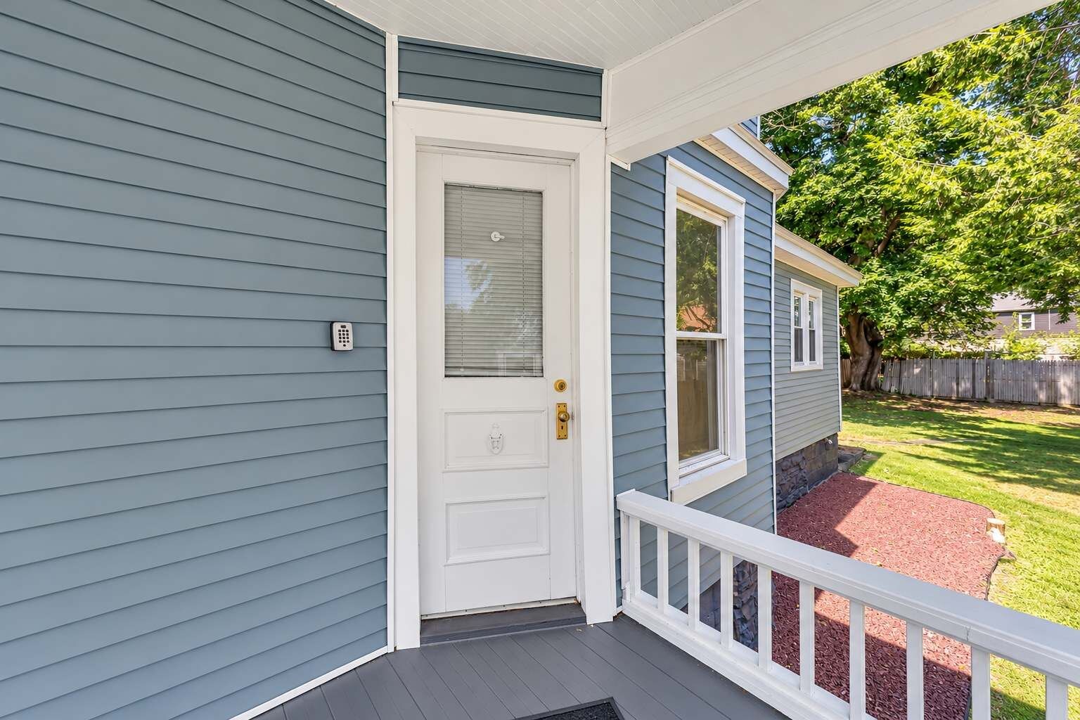 A house with a front porch, a white door, and a mailbox.