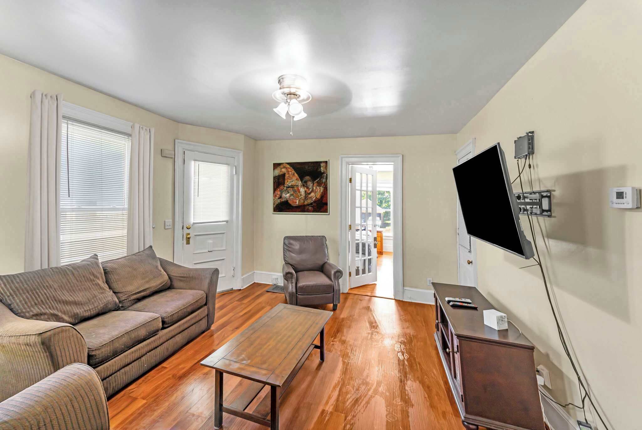 A living room with a sofa, a coffee table, a chair, and a flat-screen TV mounted on the wall.