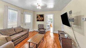 A living room with a sofa, a coffee table, a chair, and a flat-screen TV mounted on the wall. - After the Game Apt 2 - All Star Baseball Rentals (Oneonta)