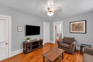 Un salon équipé d’un téléviseur à écran plat, d’un canapé marron, d’une table basse en bois et d’un ventilateur de plafond.