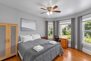 Une chambre à coucher comprenant un lit, un bureau, une chaise, une armoire et un ventilateur de plafond.