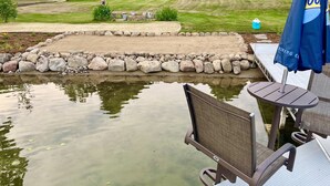 A patio area with a view of a pond, a seating arrangement, and a grassy landscape in the background. - Quiet, relaxing home on Lake Watab in beautiful St. Joseph, MN near SJU and CSB (St Joseph)
