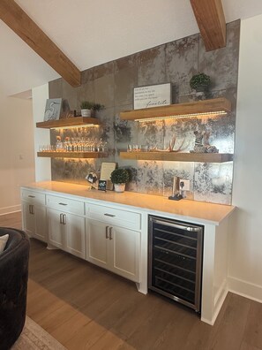 A kitchen with a built-in wine rack, a refrigerator, and a countertop with glassware. - ON THE ROCKS 2.0 BIG LAKE 🎣 (Lake Charles)