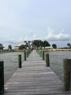 A wooden pier leading to a house by the water.