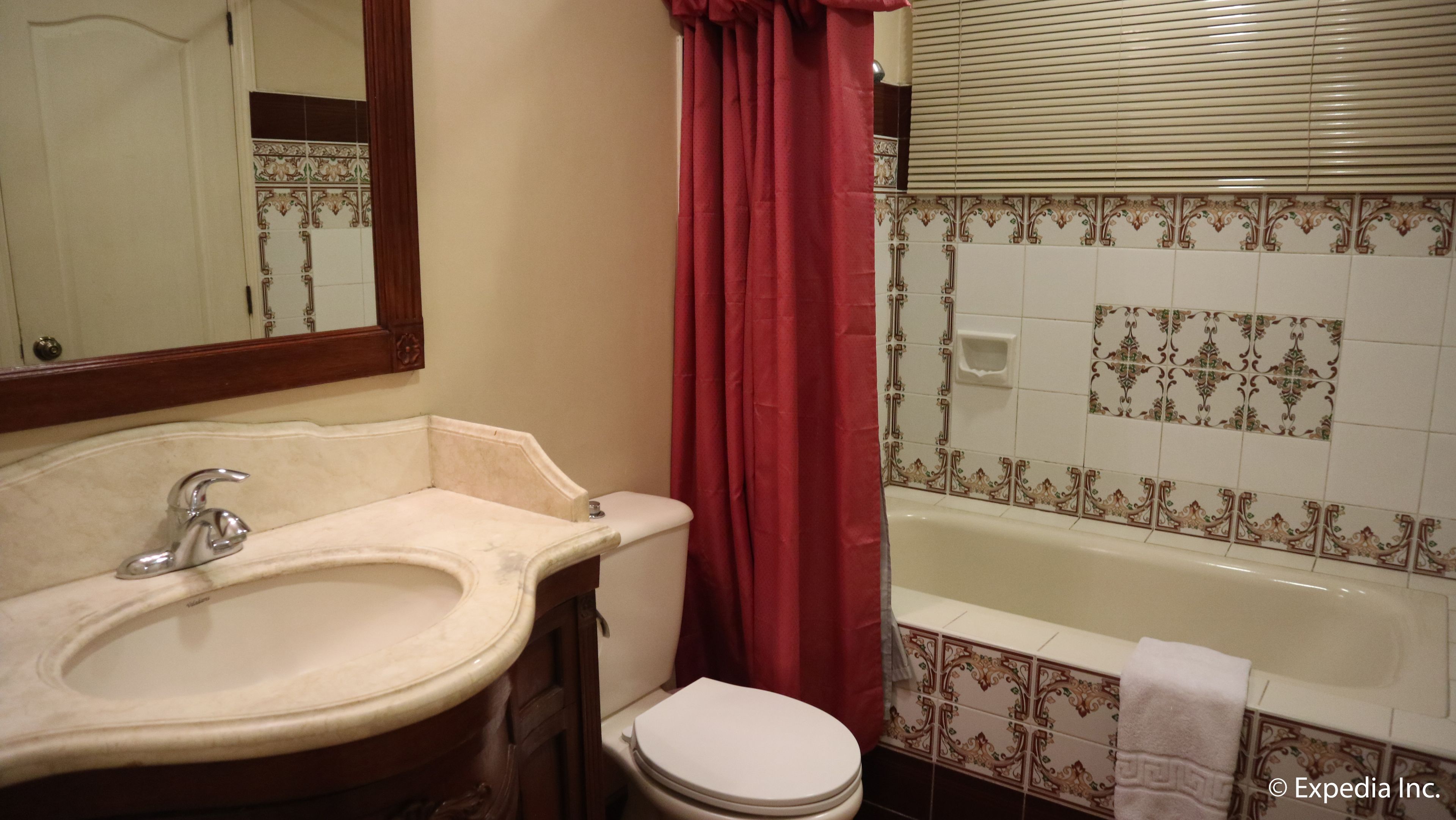 A bathroom with a sink, mirror, toilet, and bathtub.