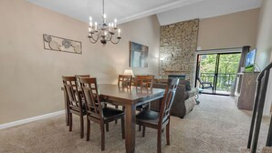 Un'area pranzo con tavolo e sedie in legno, un lampadario e una parete in pietra.
