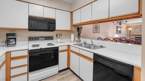 A modern kitchen with white cabinets, a black microwave, a stove, and a dishwasher. - two bedroom condo sleeps 8 persons (Gatlinburg)