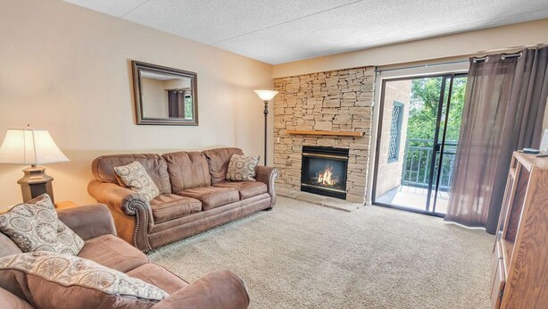 A living room with a stone fireplace, leather sofas, and a large sliding glass door leading to a balcony. - two bedroom condo sleeps 8 persons (Gatlinburg)