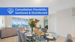 A modern dining area with a glass table, chairs, and a view of the sea. - Luminous corner condo overlooking the bay | WIFI + Netflix + Parking (Sunny Isles Beach)