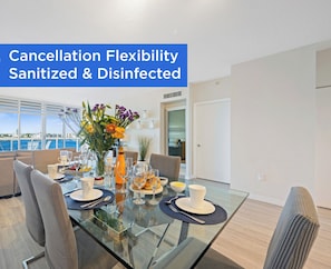 Un comedor moderno con una mesa de vidrio, sillas y vistas al mar.