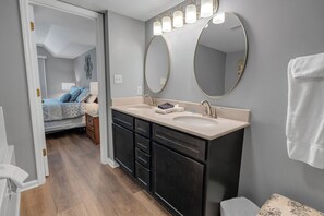 Un baño moderno con tocador de doble lavabo, un espejo grande y un vestidor.