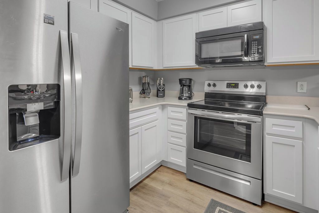 Una cocina moderna con electrodomésticos de acero inoxidable, armarios blancos y un microondas integrado.