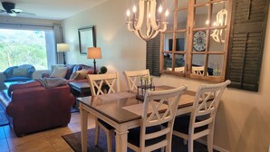 A dining area with a wooden table and chairs, a chandelier, and a large mirror with shutters. - Perfect condo in foothills of the Catalina Mountains with Spectacular Views (Tucson)