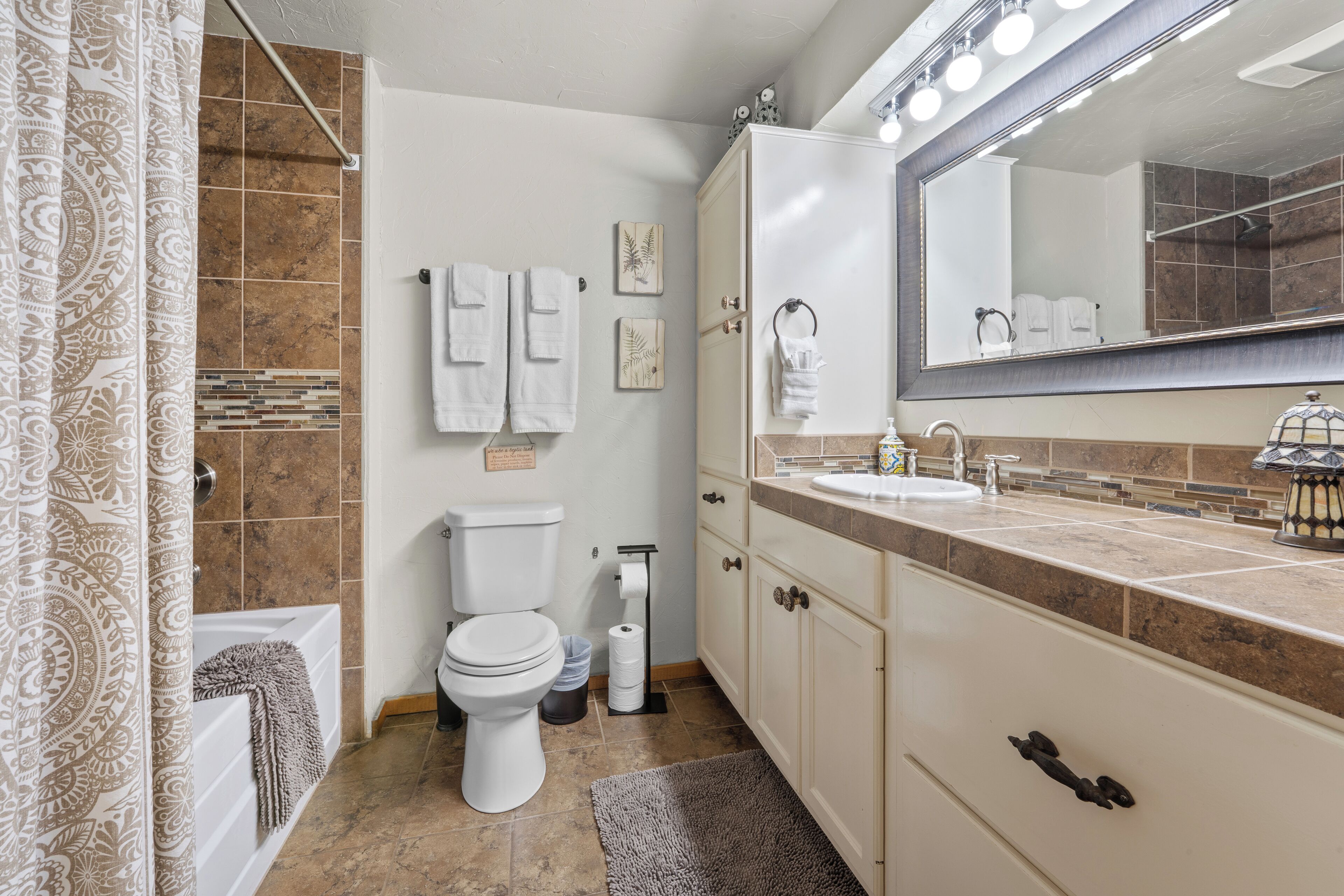 Une salle de bain équipée d’une baignoire, de toilettes, d’un meuble-lavabo avec un miroir et de serviettes.