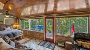 L’intérieur chaleureux d’un chalet comprend un lit, un coin salon et de grandes fenêtres qui offrent une vue sur l’extérieur.